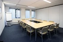 Vergaderruimte aan de Utrechtseweg met U-vormige tafelopstelling, stoelen en een flip-over.
