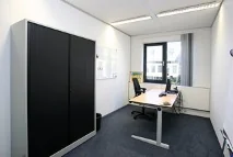 Klein en modern ingericht kantoor aan de Utrechtseweg met bureau, stoelen en een opbergkast.