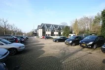 Parkeerterrein met geparkeerde auto's voor een kantoorpand aan de Utrechtseweg.