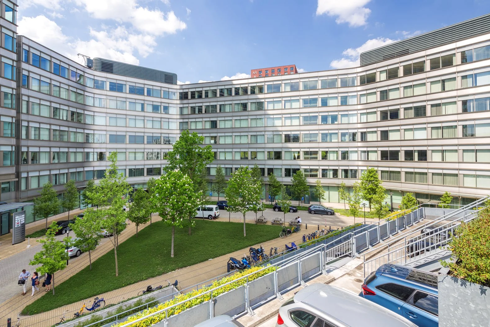 Moderne kantoorgebouwen aan de Europalaan met een groen binnenplein, geparkeerde auto’s en fietsen.