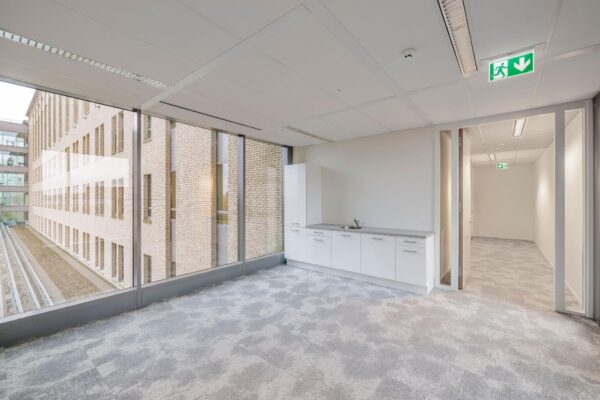 Moderne kantoorruimte aan de Mercatorlaan met pantry, grote raampartij en zicht op een aangrenzend kantoorgebouw.