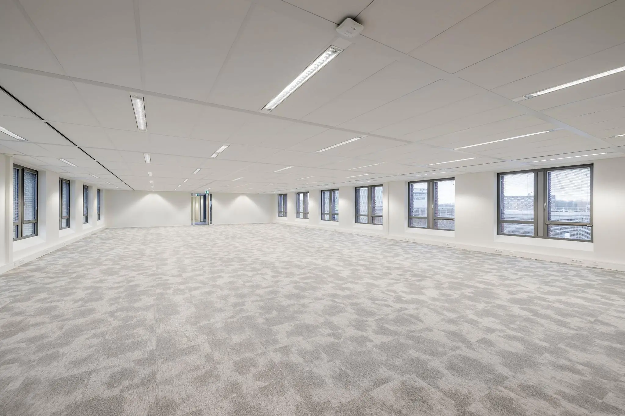 Licht en ruim leeg kantoorinterieur aan de Mercatorlaan met grote ramen en grijze vloerbedekking.