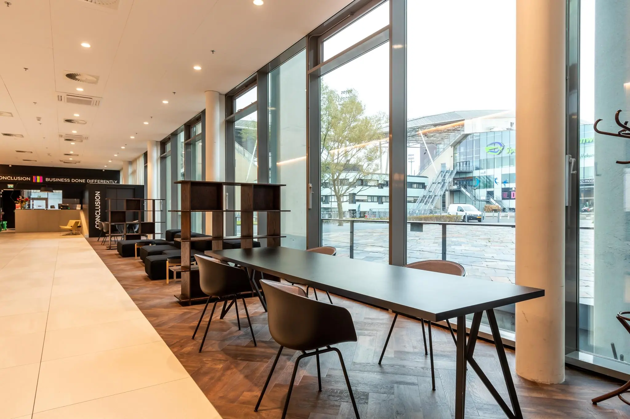 Moderne kantoorlounge met werkplekken en uitzicht op het Herculesplein in Utrecht.