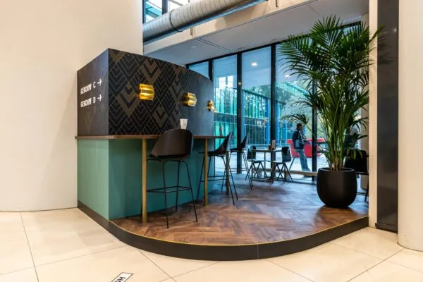 Moderne wachtruimte met hoge stoelen, planten en bewegwijzering naar gebouw C en D op Herculesplein.