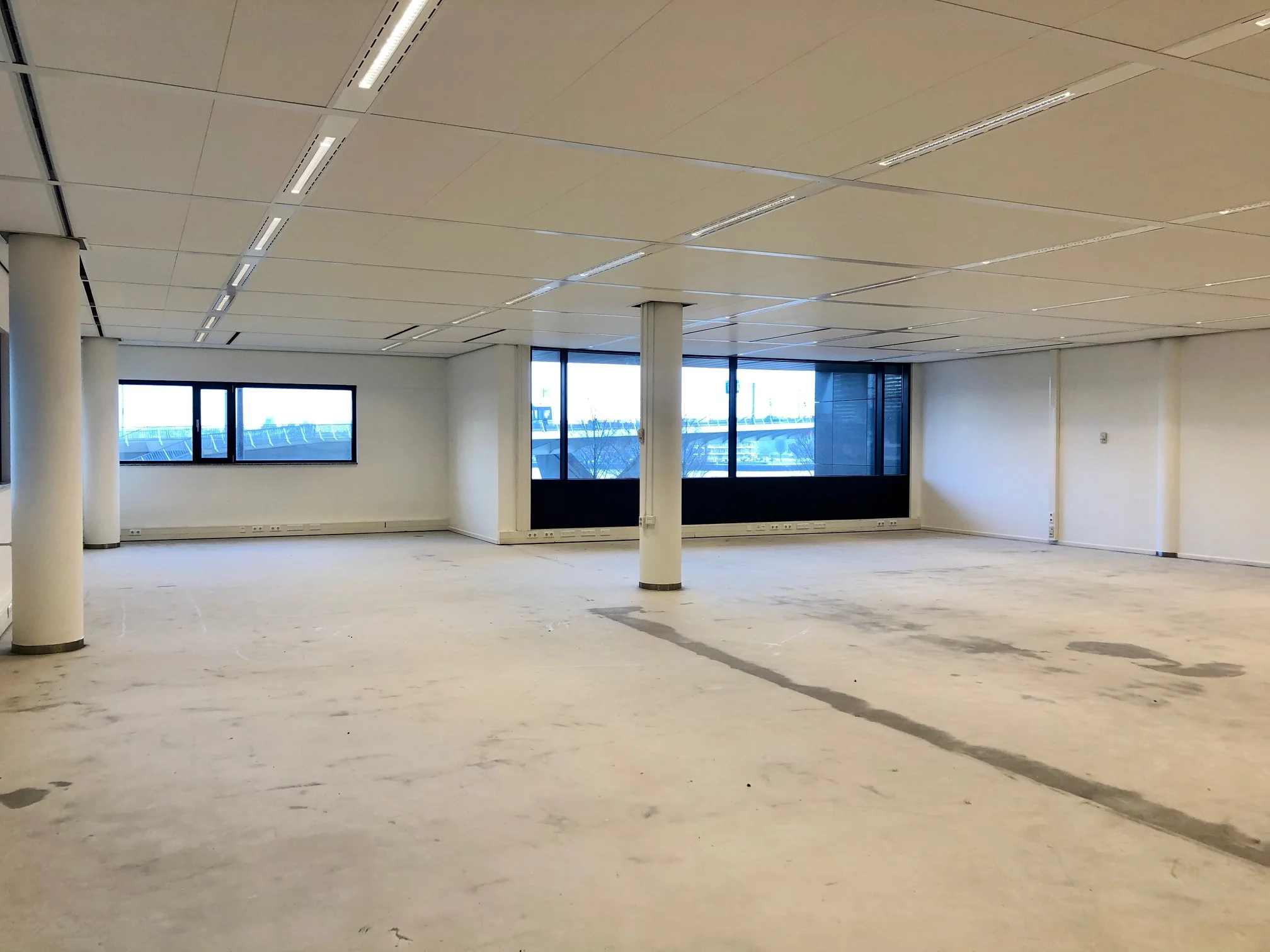 Leeg kantoorpand aan het Willemsplein met grote ramen en systeemplafond.