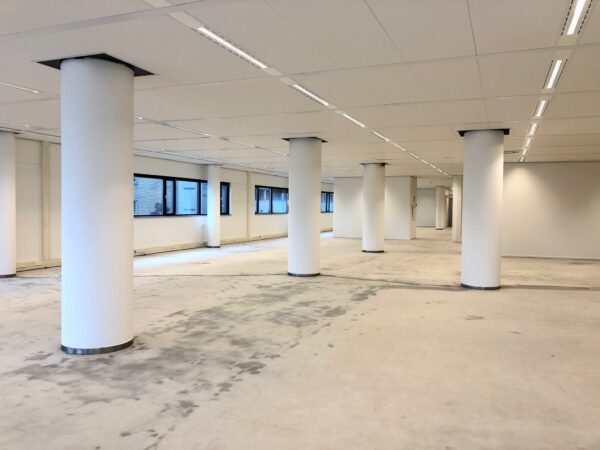Leeg kantoorpand aan het Willemsplein met witte pilaren en systeemplafond.