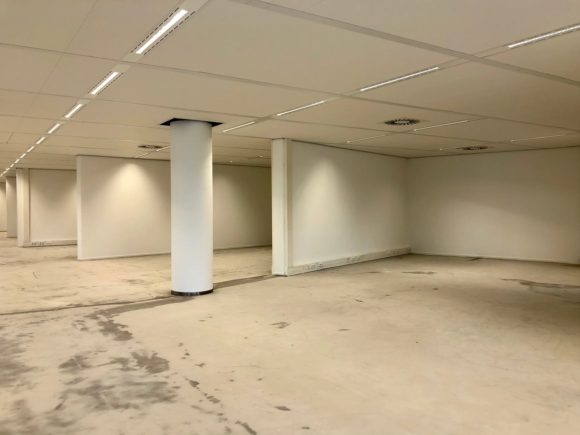 Leegstaand kantoorpand aan het Willemsplein met witte muren, systeemplafond en betonnen vloer.