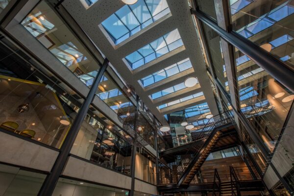 Modern atrium van een kantoorpand aan de Fokkerstraat met glazen dak, open trappenhuis en designverlichting.