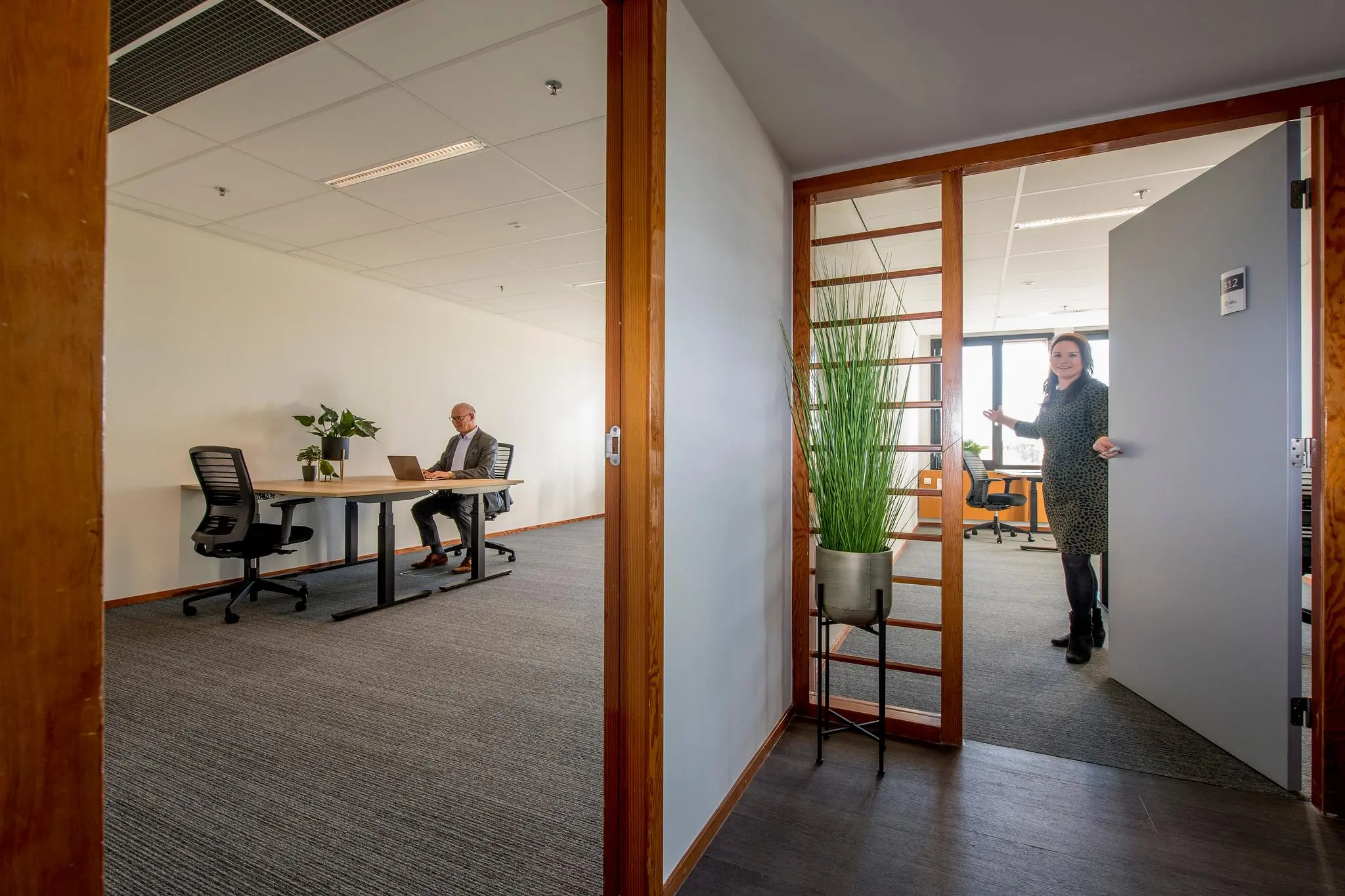 Kantoorruimte aan de Fokkerstraat met een man aan het werk en een vrouw die een deur opent.