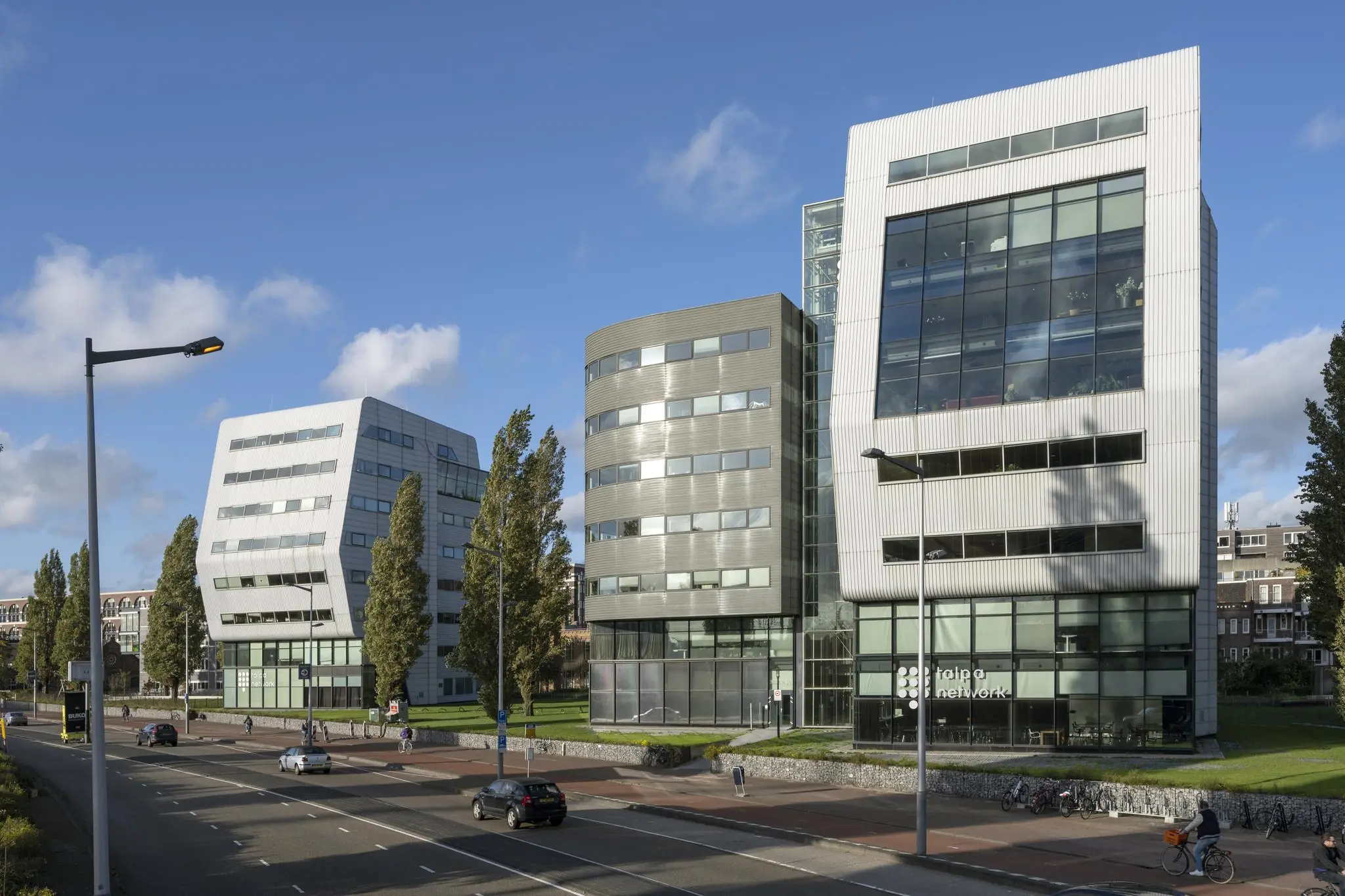 Drie moderne kantoorgebouwen aan het Rietlandpark in Amsterdam met opvallende gevelarchitectuur en grote ramen.