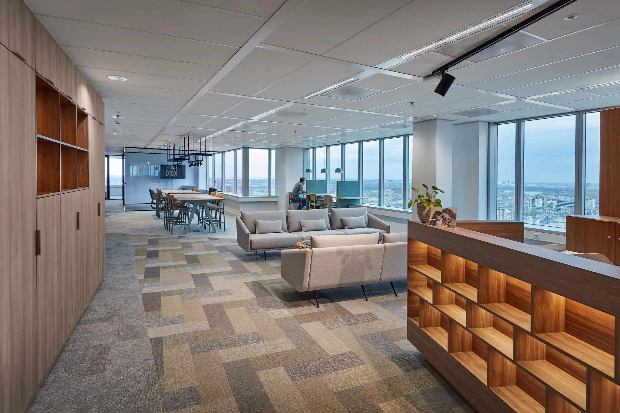 Modern ingericht kantoorinterieur in De Blaak met zithoeken, werkplekken en uitzicht op de stad.