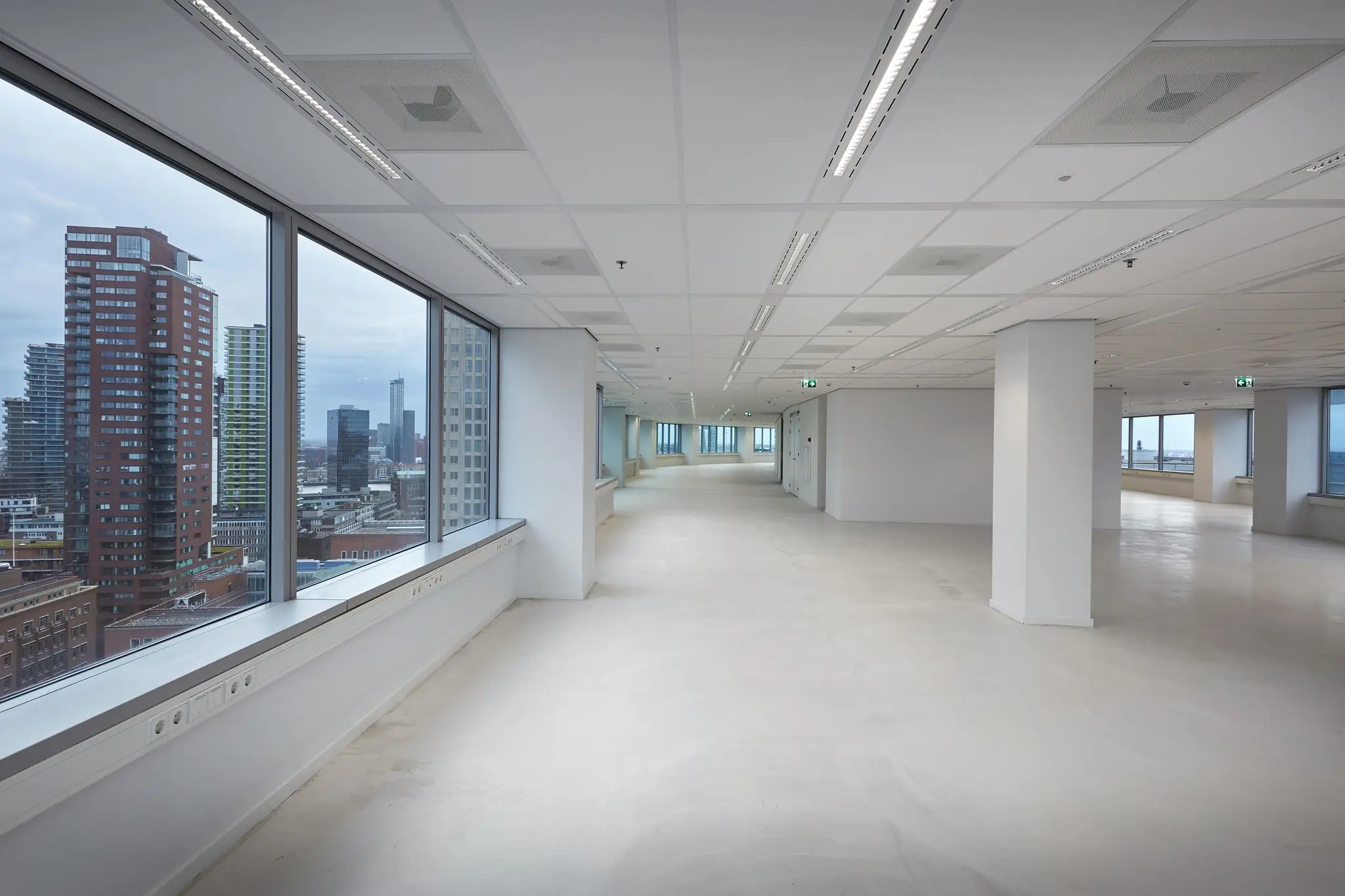 Licht en modern leeg kantoorpand met uitzicht op de hoogbouw van Rotterdam Blaak.