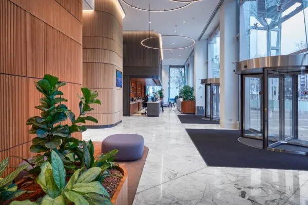 Moderne ontvangsthal van Blaak 16 in Rotterdam met marmeren vloer, houten wanden, planten en een receptiebalie.