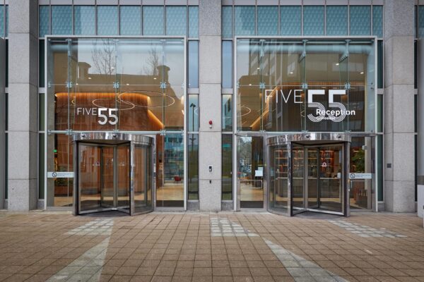 Hoofdingang van kantoorgebouw FIVE55 aan de Blaak met glazen gevel en draaideuren.
