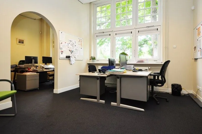 Modern kantoor met bureaus en computers, gelegen aan de Spechtlaan met groot raam en veel daglicht.
