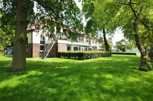 Appartementencomplex aan de Spechtlaan met ruime groene tuin en omringende bomen.