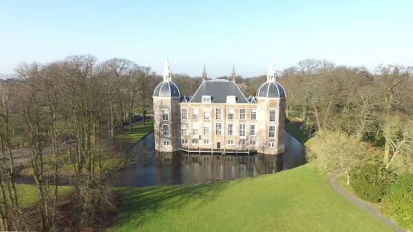Luchtfoto van Kasteel Middachten aan de Kasteellaan, omringd door een gracht en bomen.