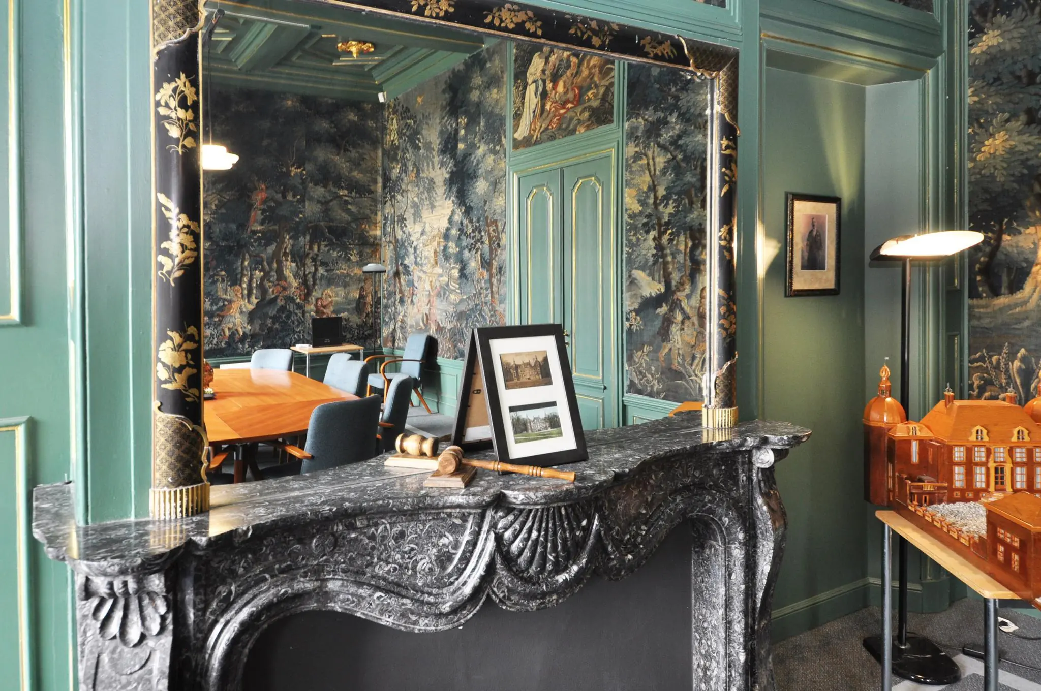 Klassiek ingerichte vergaderruimte in Kasteellaan met een marmeren haard, wandtapijten, maquette en historische foto's.