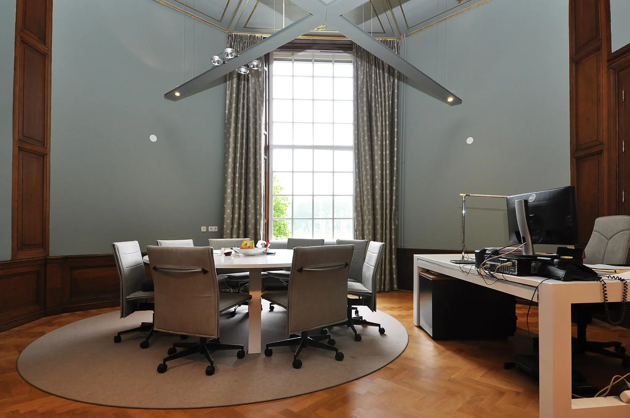 Vergaderruimte in een statig gebouw aan de Kasteellaan, met ronde tafel, moderne bureaustoelen en groot klassiek raam.