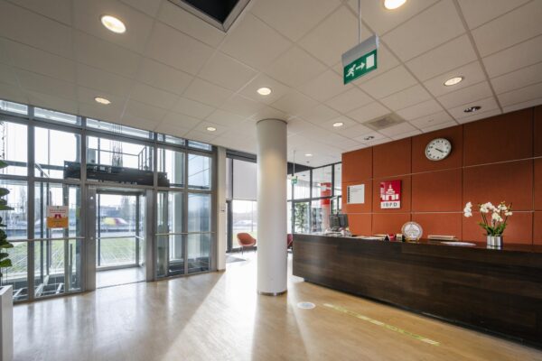 Receptiehal van het IBFD-kantoor in Rietlandpark met balie, klok en glazen entree.