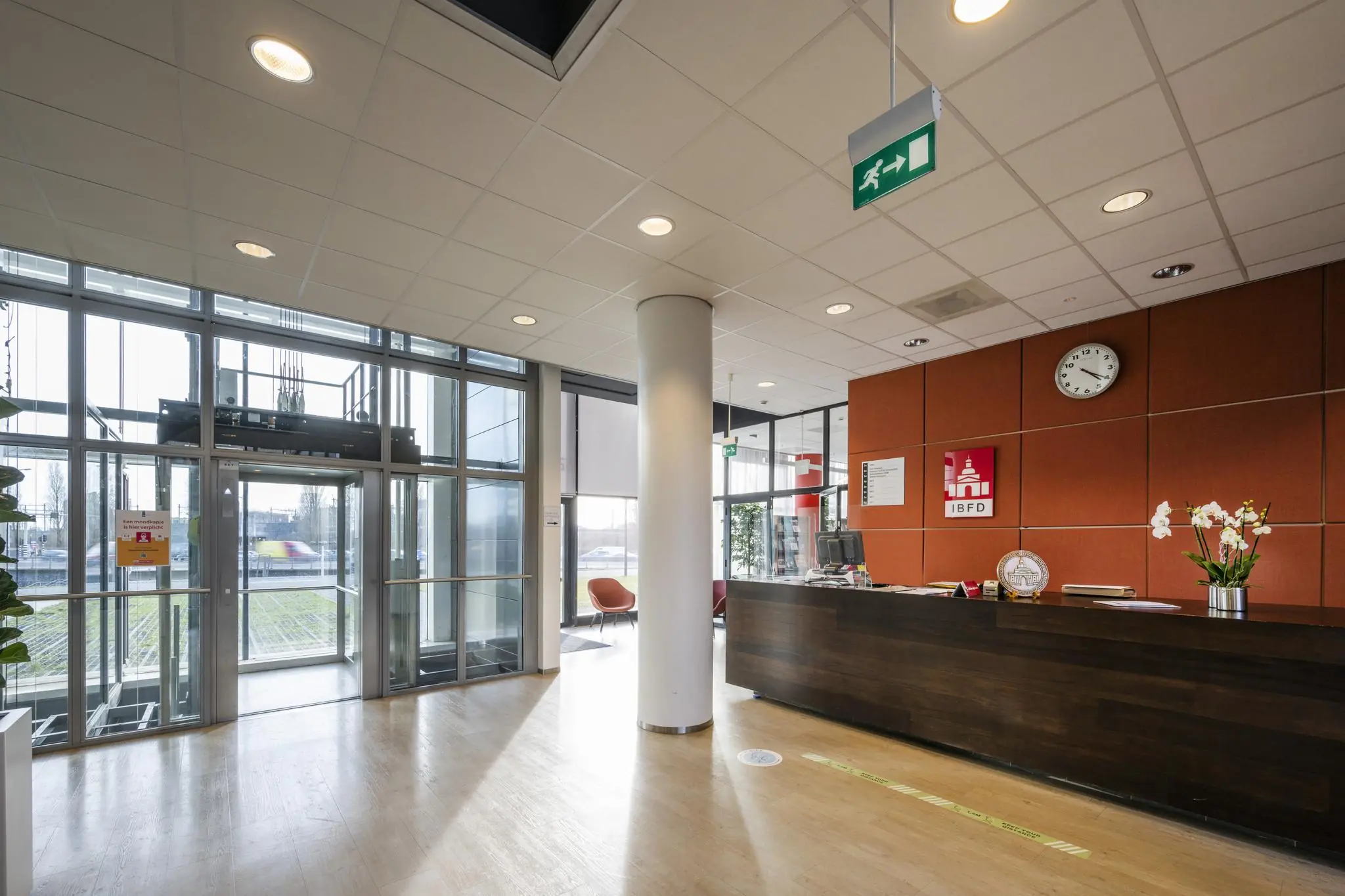 Receptiehal van het IBFD-kantoor in Rietlandpark met balie, klok en glazen entree.
