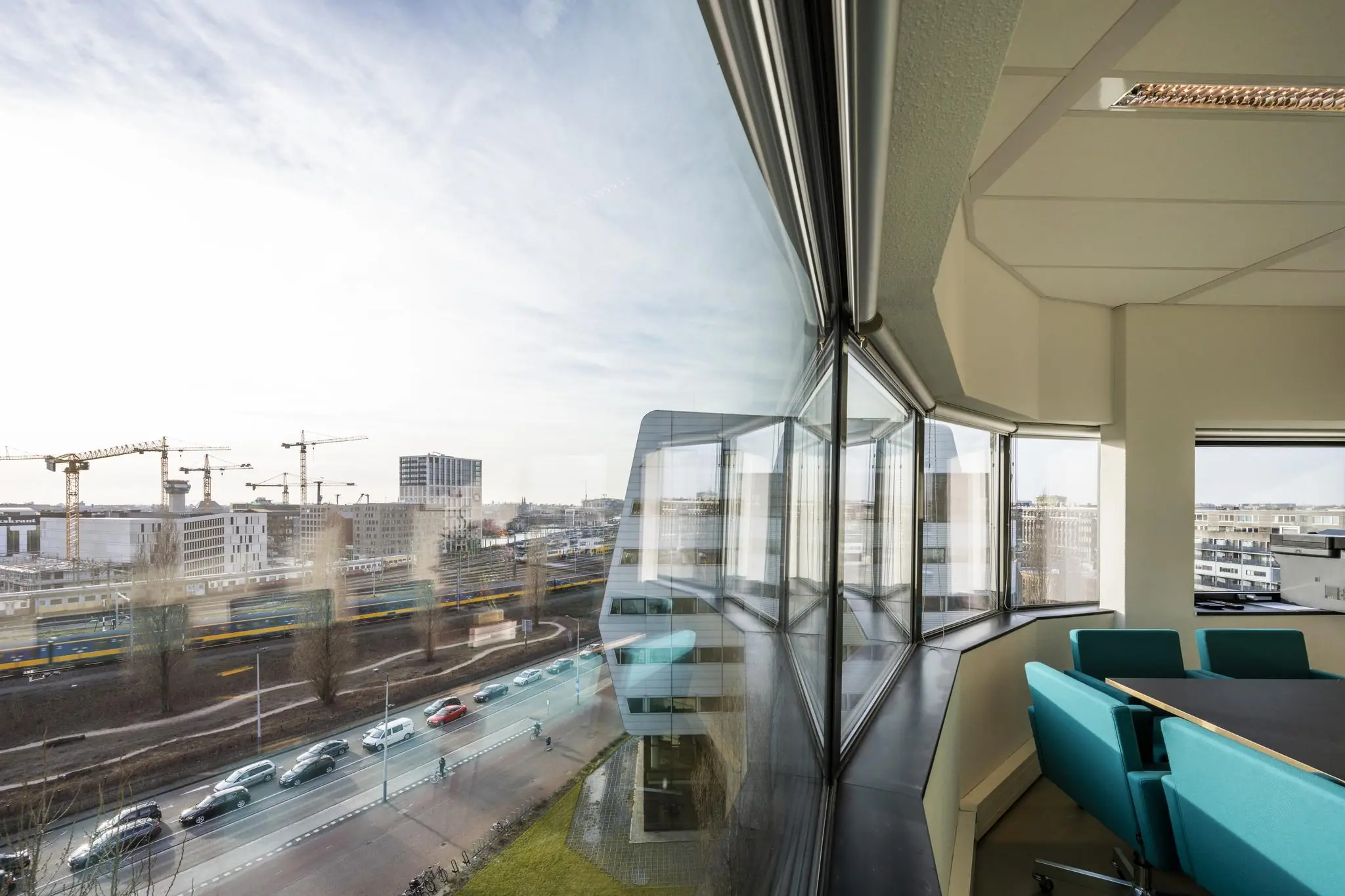 Vergaderruimte met uitzicht op Rietlandpark, spoorlijn en bouwkranen in Amsterdam.