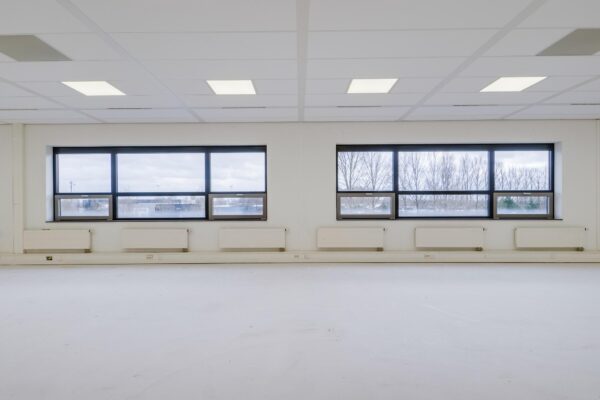 Lege, lichte kantoorruimte aan de Marconibaan met grote ramen en wit plafond.