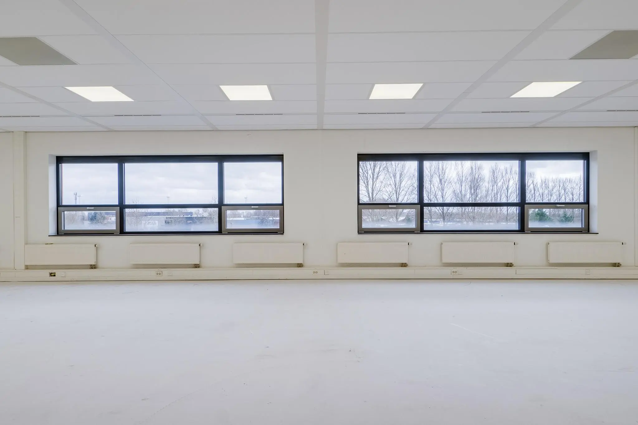 Lege, lichte kantoorruimte aan de Marconibaan met grote ramen en wit plafond.
