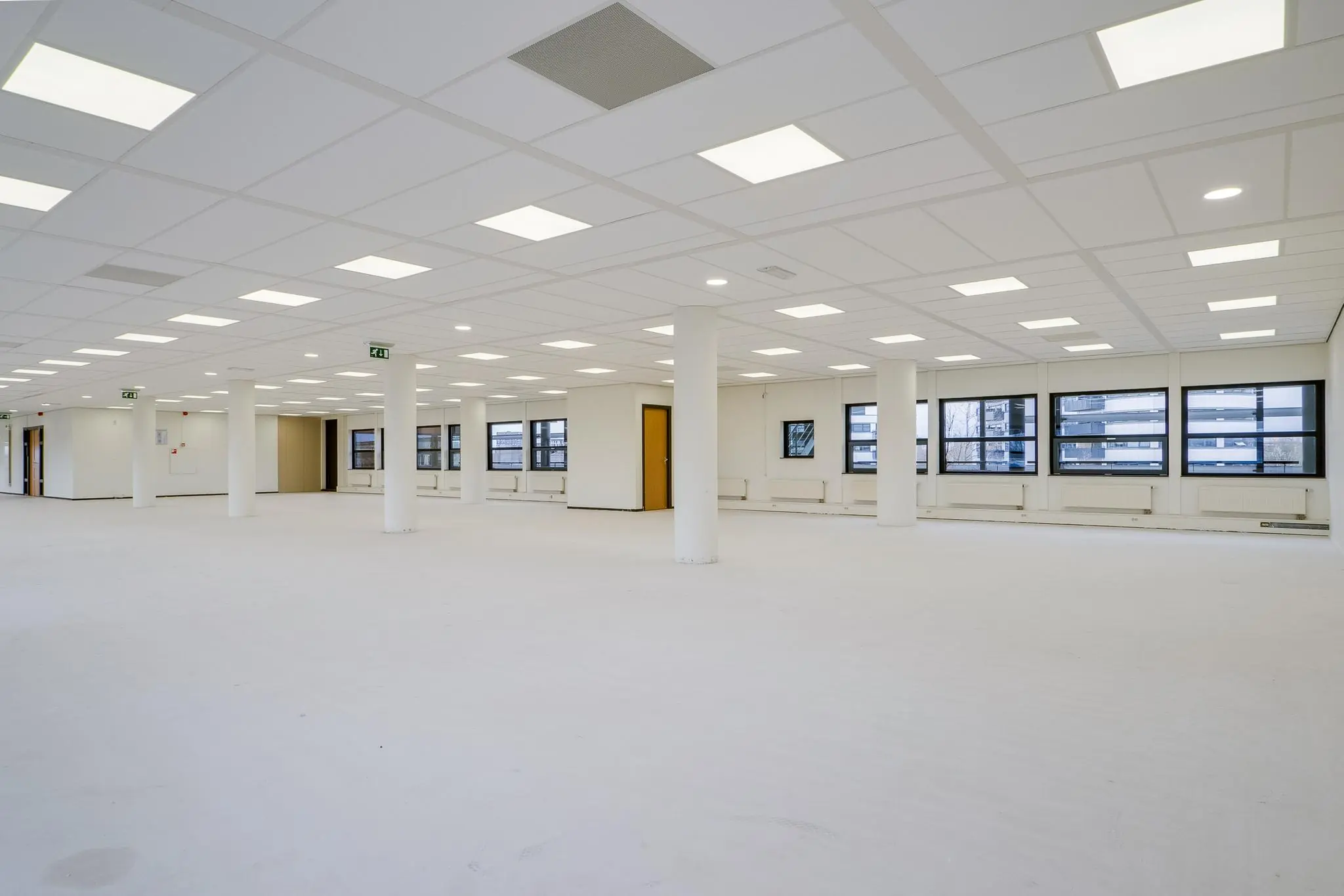 Lichte, lege kantoorruimte aan de Marconibaan met systeemplafond, witte muren en grote ramen.