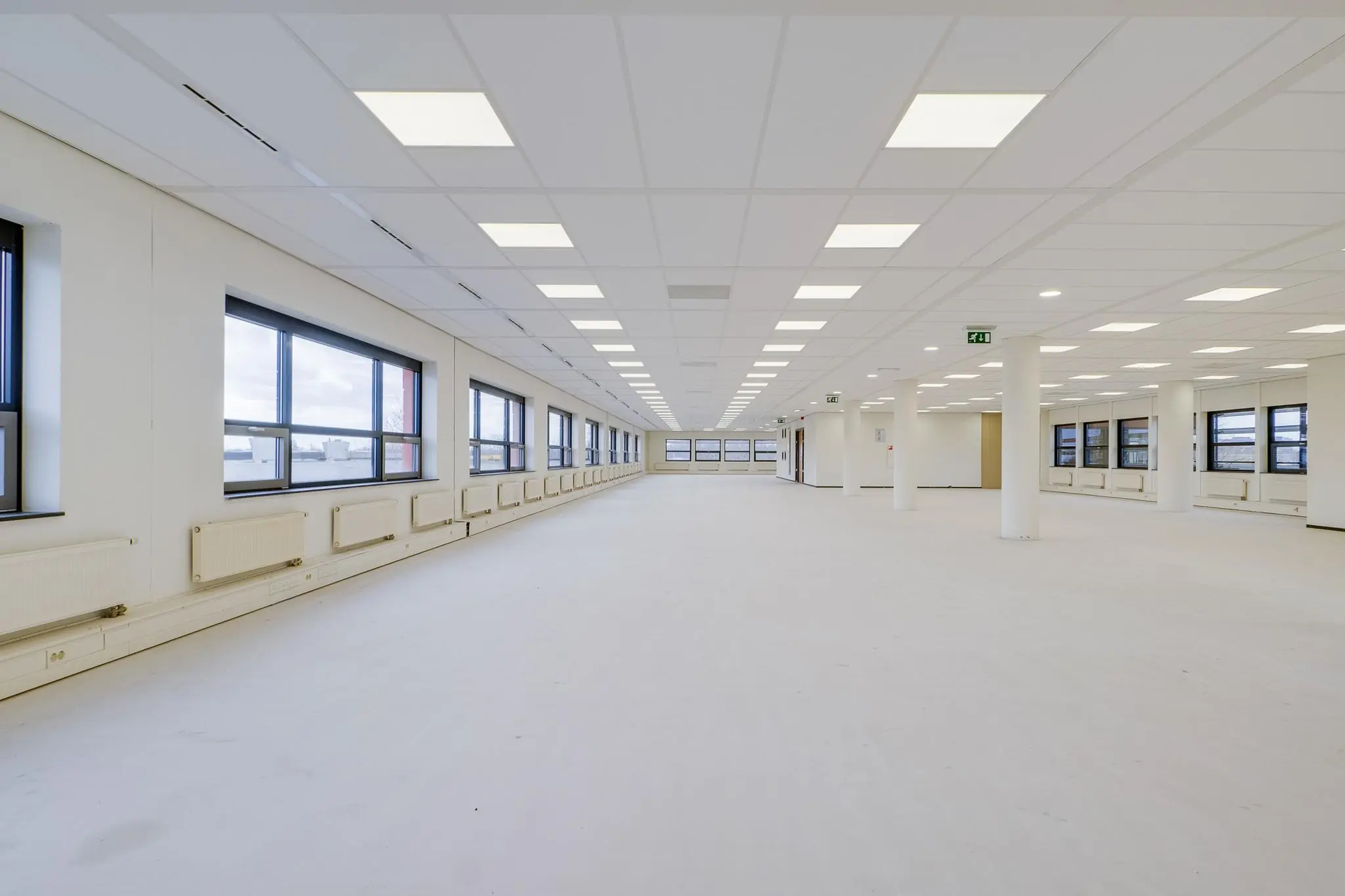 Lichte, lege kantoorruimte aan de Marconibaan met systeemplafond en grote ramen.