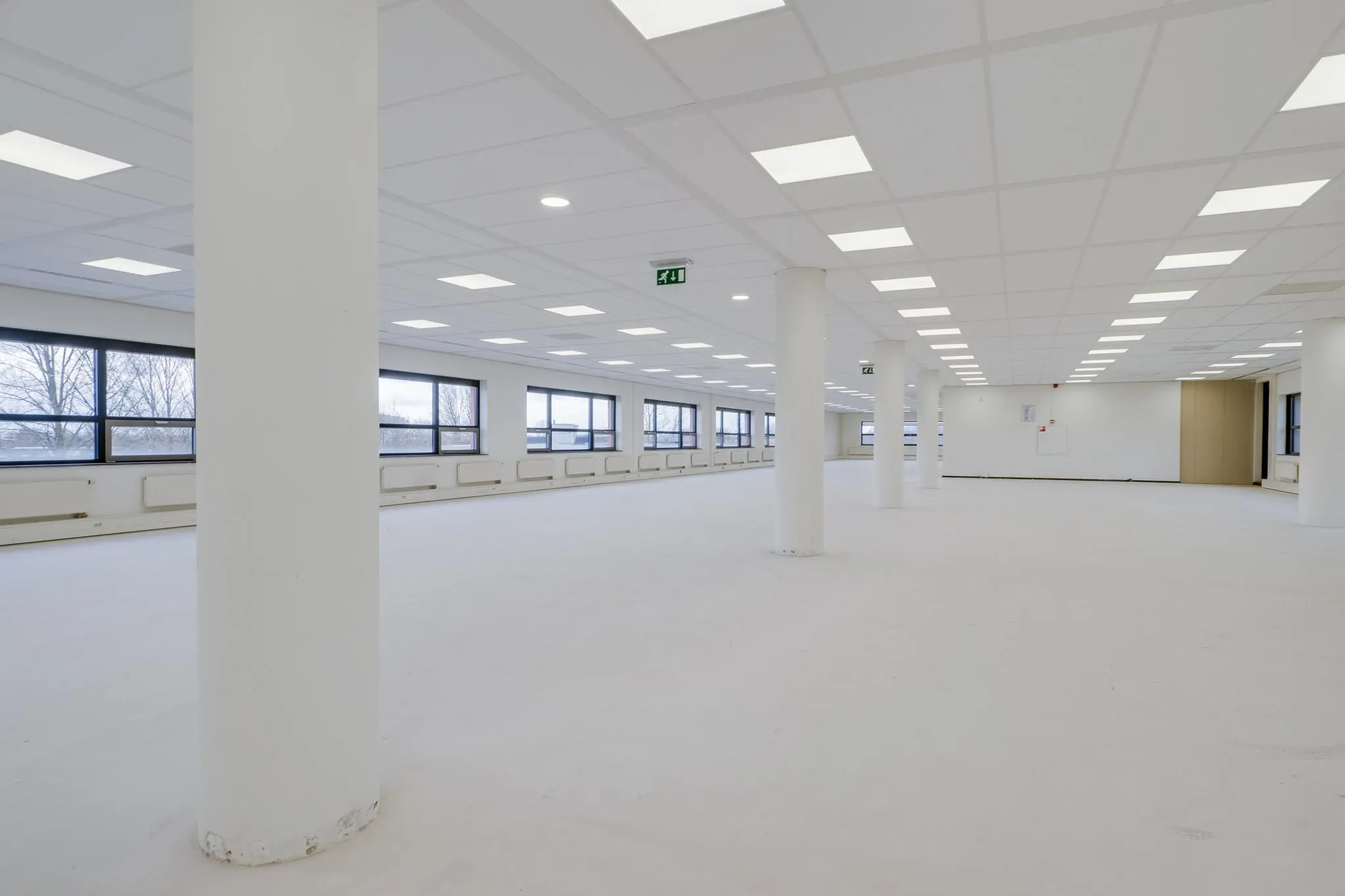 Een grote, lege en licht verlichte kantoorruimte aan de Marconibaan met witte wanden, plafond en vloer.