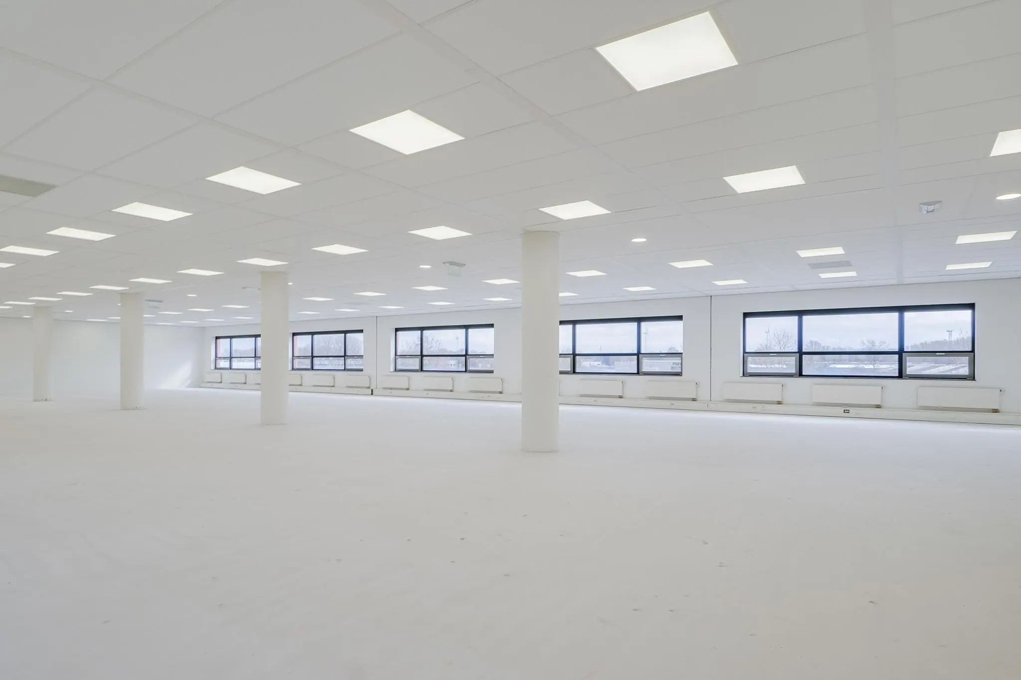 Lichte, lege kantoorruimte aan de Marconibaan met systeemplafond en grote ramen.
