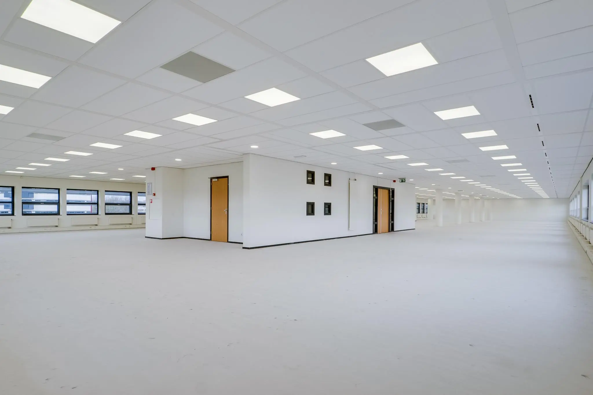 Ruime, lege kantoorruimte aan de Marconibaan, met systeemplafond, witte muren en grote ramen.