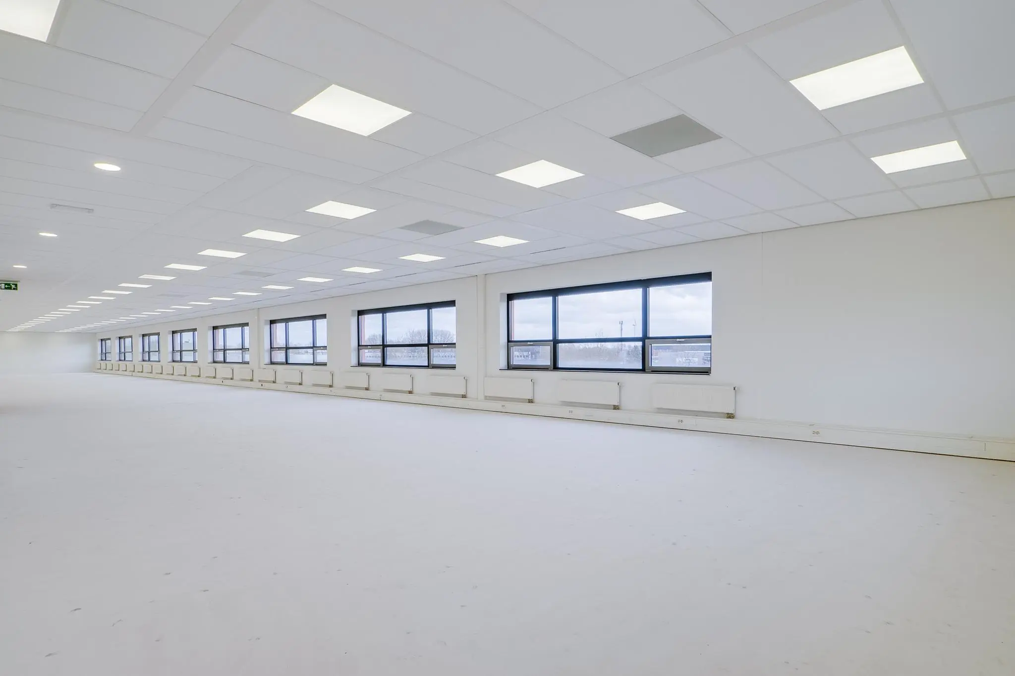 Lichte, lege kantoorruimte aan de Marconibaan met grote ramen en systeemplafondverlichting.