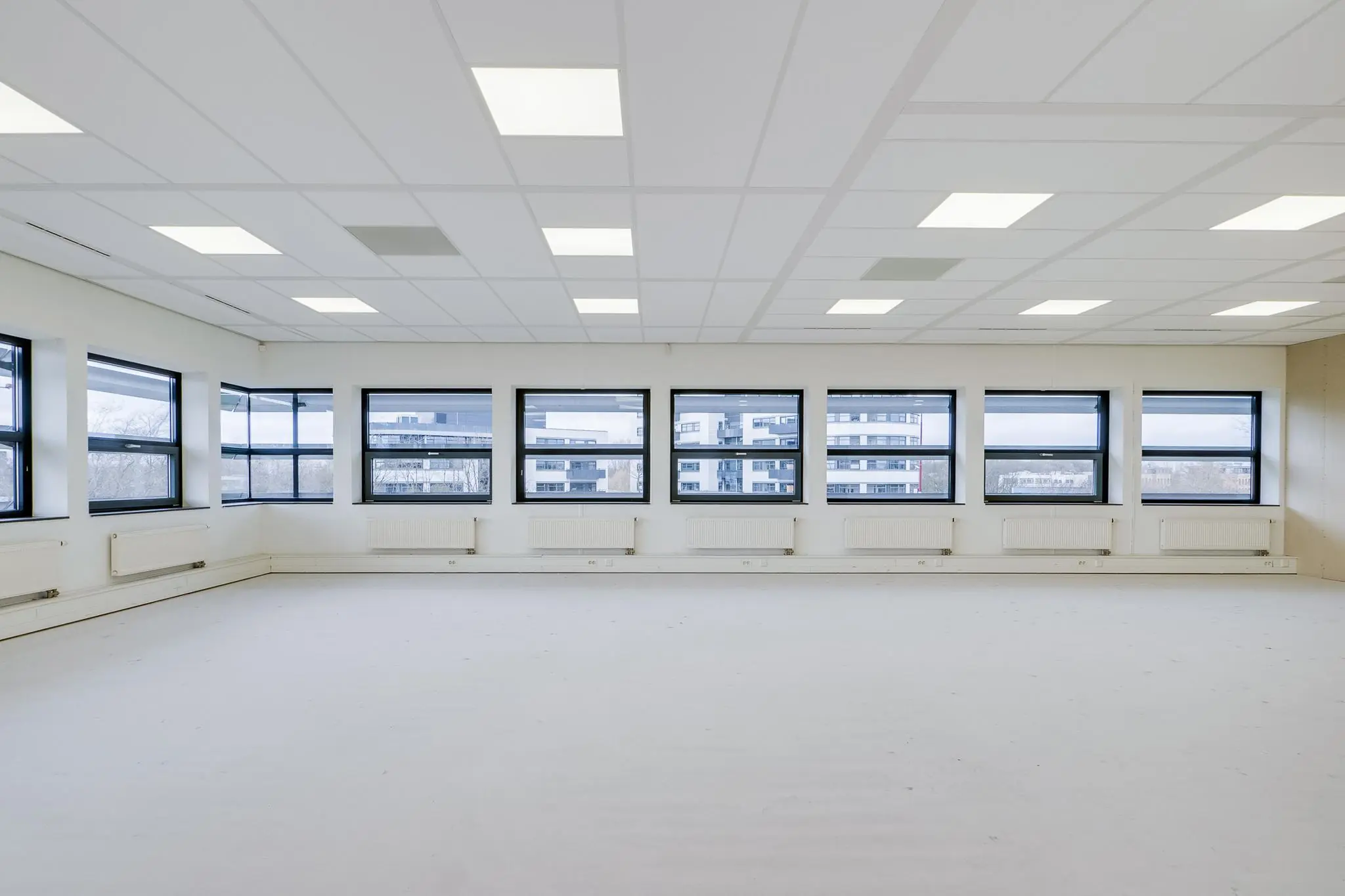 Lichte, lege kantoorruimte aan de Marconibaan met grote ramen en systeemplafond.