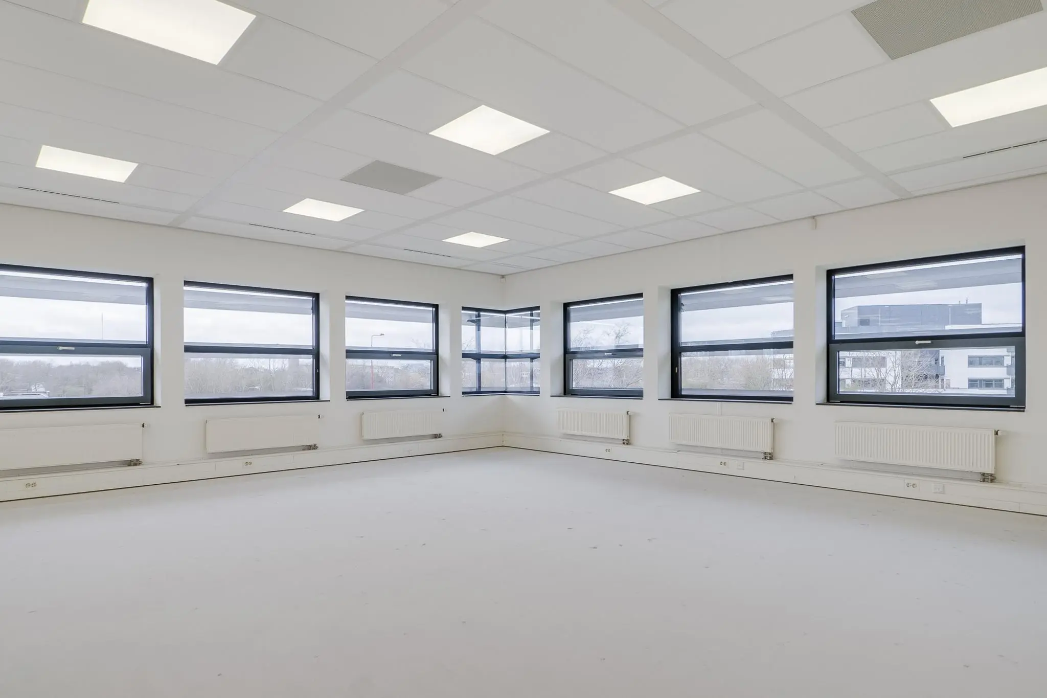Lichte, lege kantoorruimte aan de Marconibaan met grote ramen en systeemplafond.