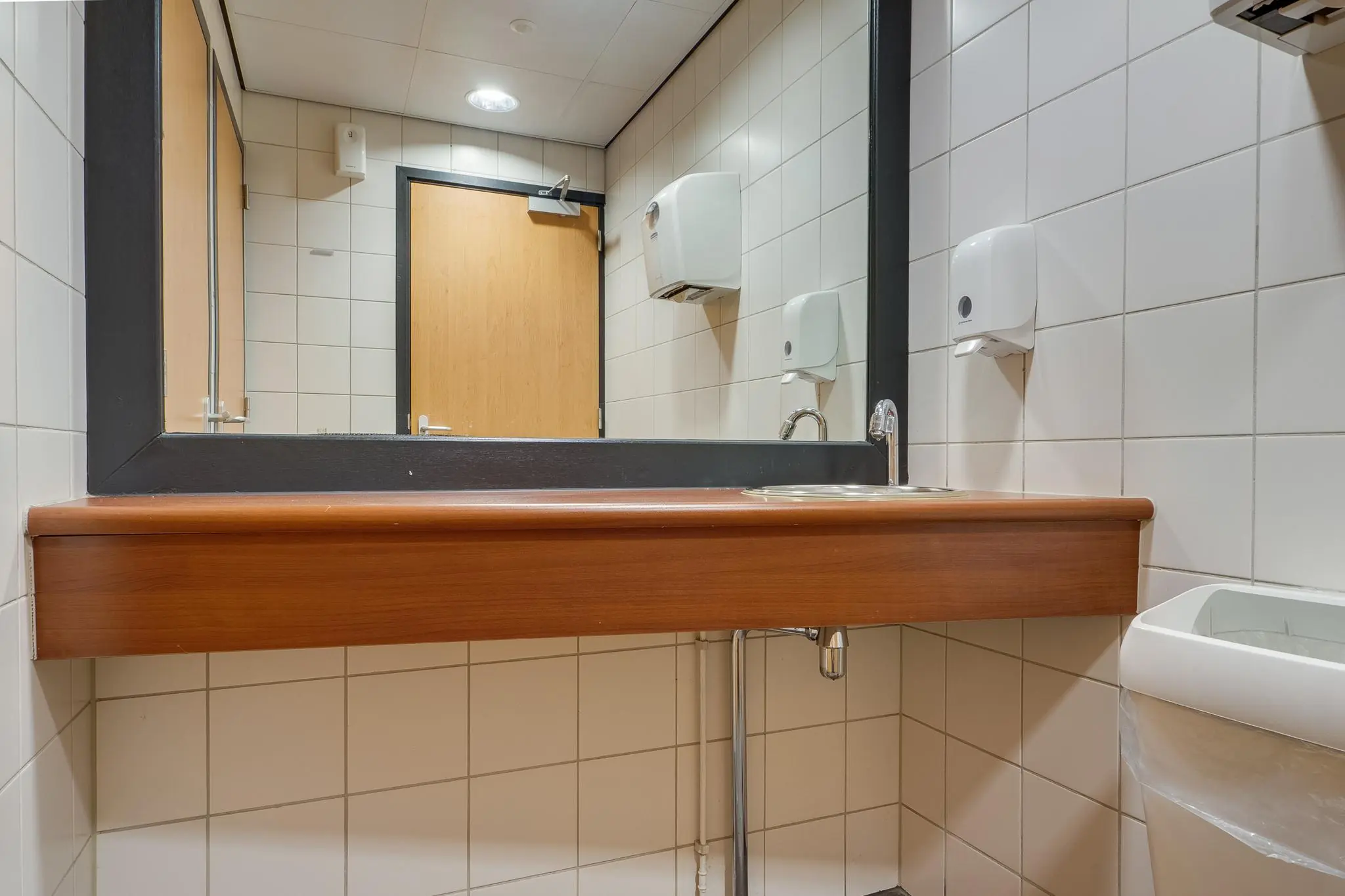 Wastafel met spiegel in een openbare toiletruimte aan de Marconibaan.