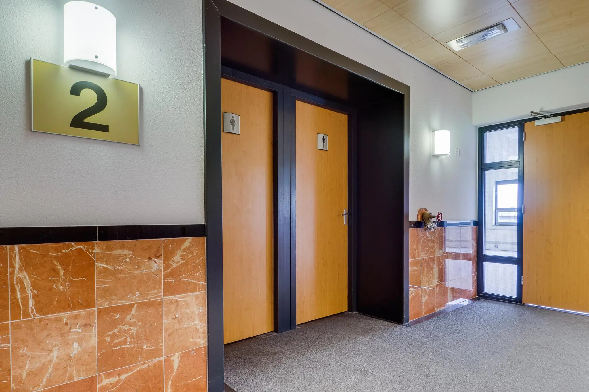 Hal met twee toiletdeuren op de tweede verdieping van een kantoorpand aan de Marconibaan.