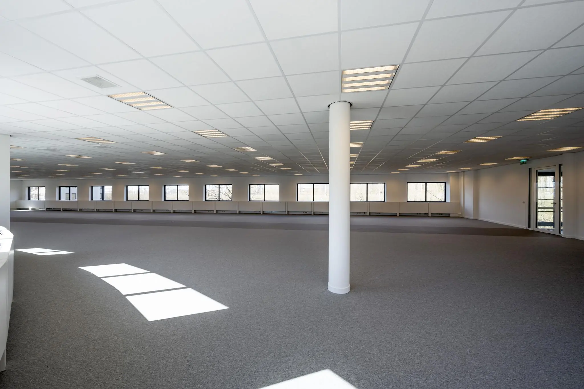 Ruime, lege kantoorruimte aan de Wegalaan met veel ramen en systeemplafond.