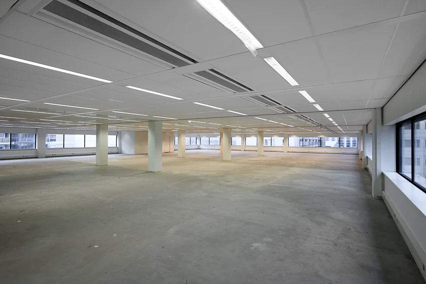 Leeg, modern kantoorpand met betonnen vloer en grote ramen aan de Weena-Zuid.