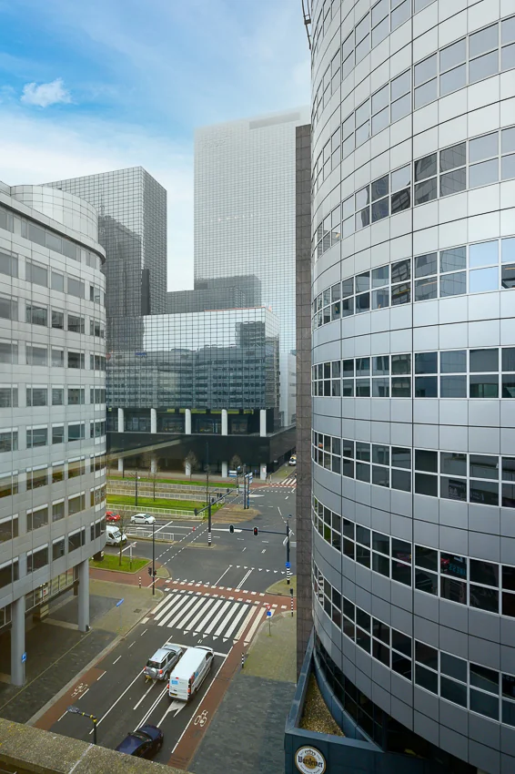 Uitzicht op moderne kantoorgebouwen aan de Weena Zuid in Rotterdam met een kruispunt en zebrapad op de voorgrond.