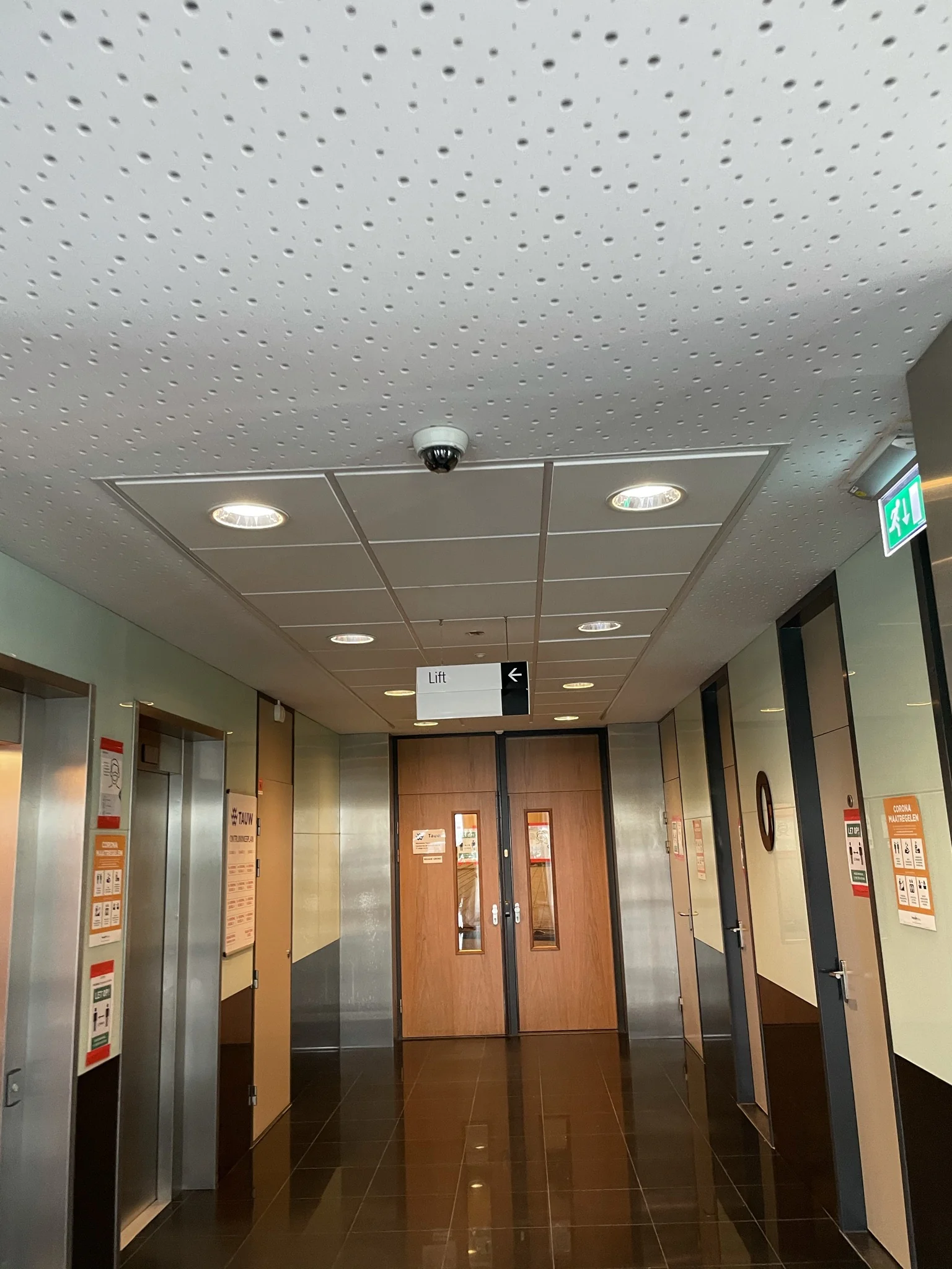 Hal met liften en deuren in het Rhijnspoorgebouw, met herkenbare bewegwijzering en informatieposters op de muren.