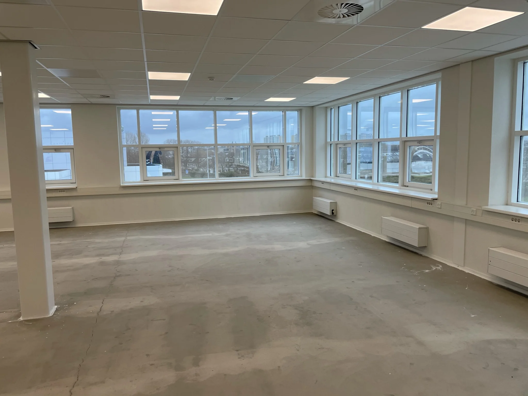 Leeg kantoorpand aan het Rhijnspoor met grote ramen en systeemplafond.