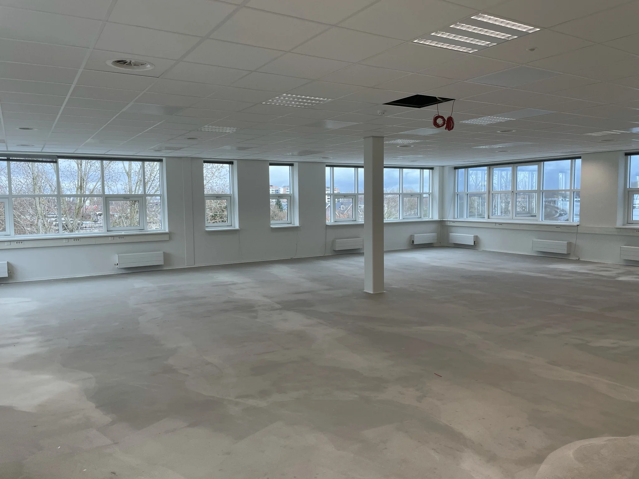 Leegstaand kantoorpand aan het Rhijnspoor met grote ramen en systeemplafond.