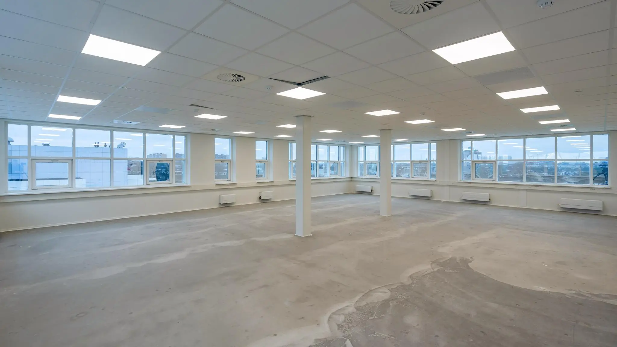 Lichte, lege kantoorruimte in het Rhijnspoorkwartier met grote ramen en systeemplafond.