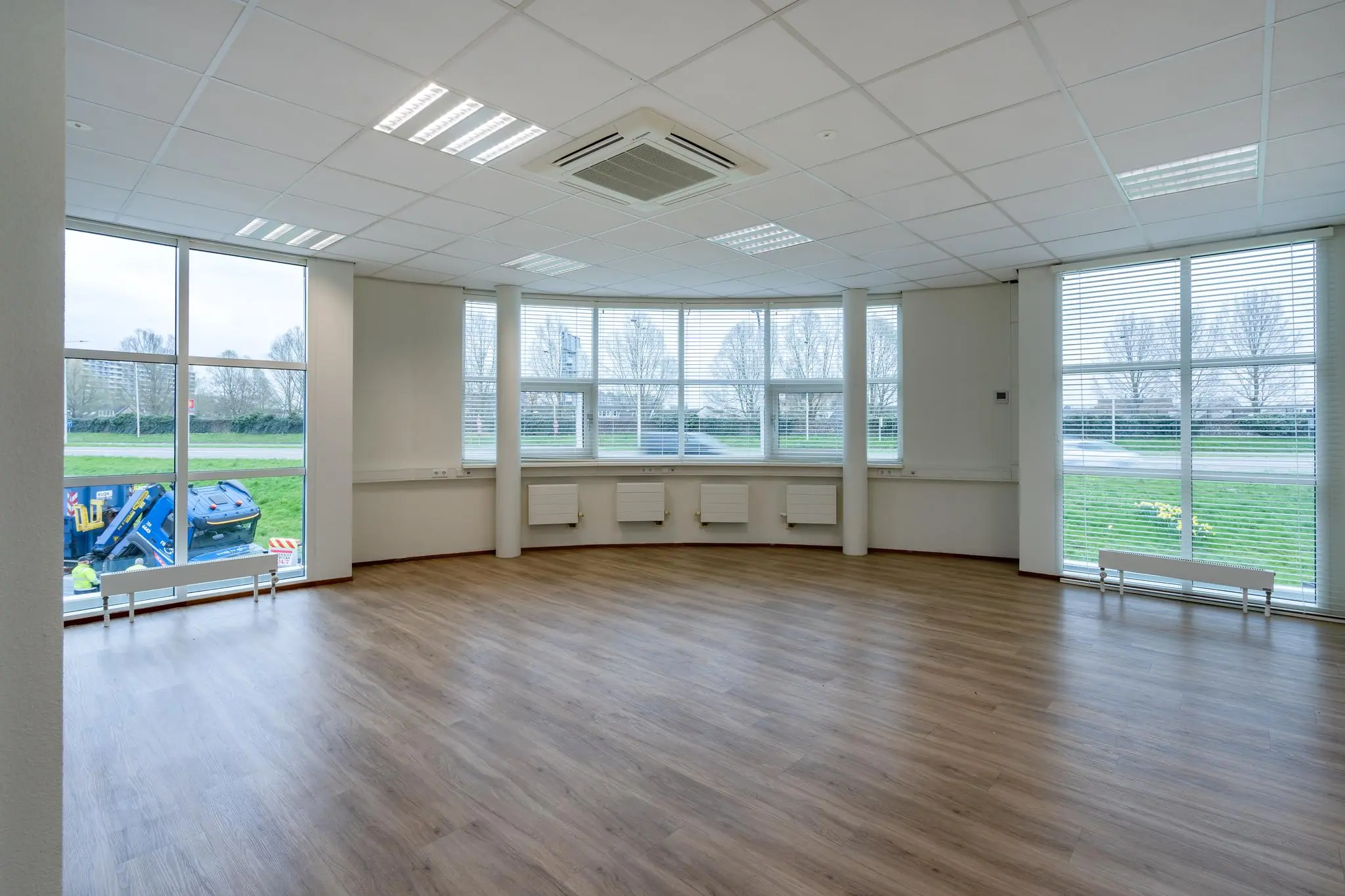 Lichte, lege kantoorruimte aan het Rhijnspoor met grote ramen en houten vloer.
