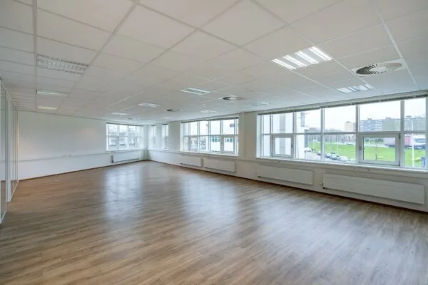 Lichte, lege kantoorruimte met laminaatvloer en grote ramen aan de Rhijnspoor.