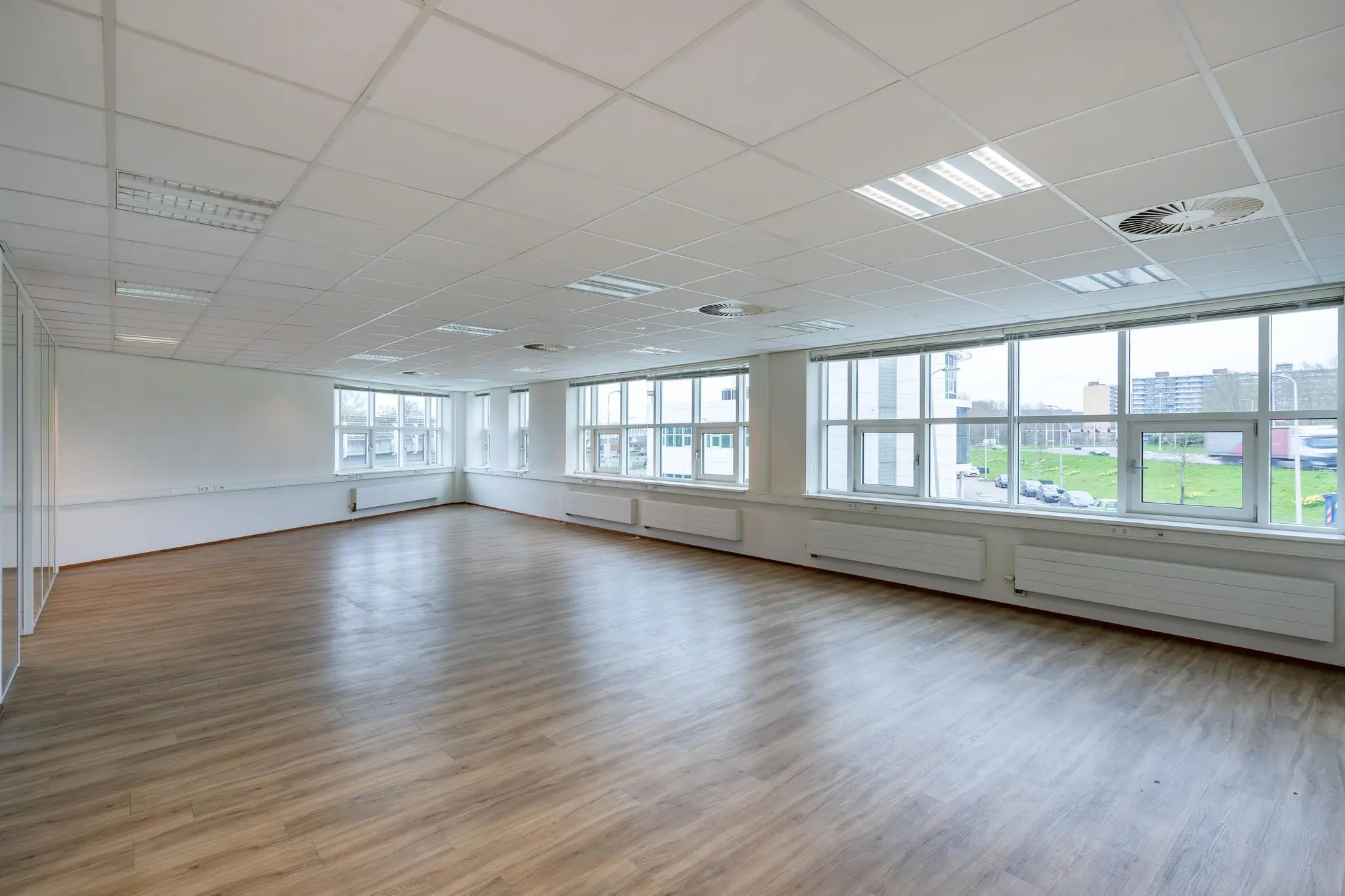 Lichte, lege kantoorruimte met laminaatvloer en grote ramen aan de Rhijnspoor.