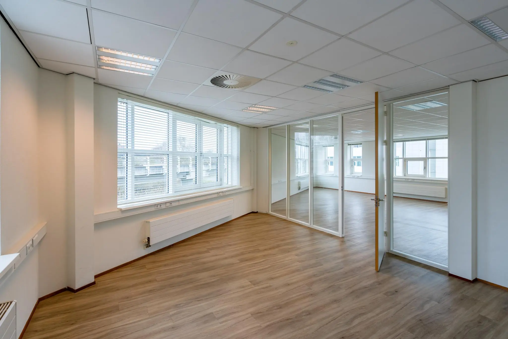 Licht en modern kantoorpand aan het Rhijnspoor met glazen scheidingswand en houten vloer.