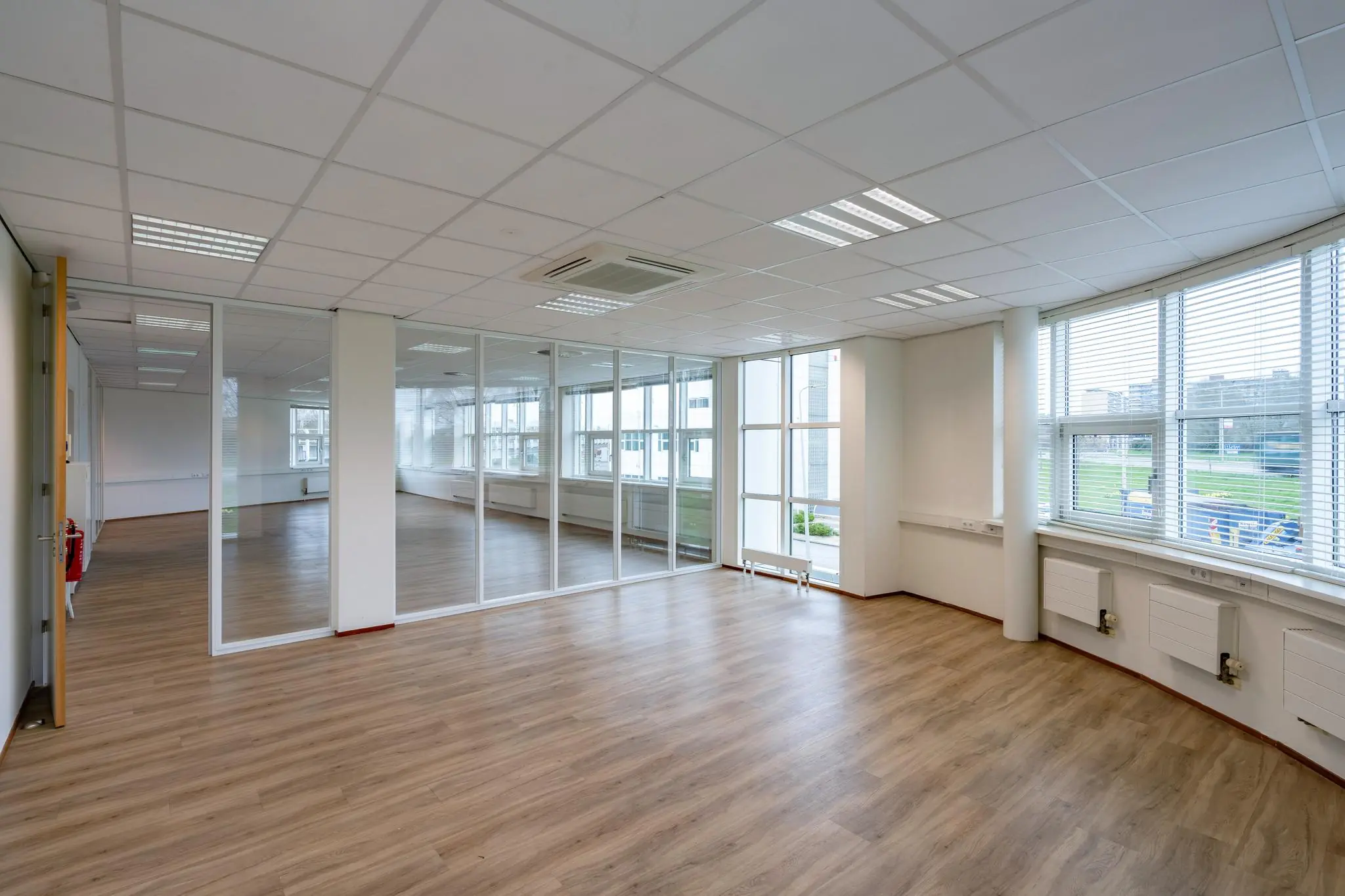 Licht en modern kantoorpand aan het Rhijnspoor met glazen scheidingswanden en grote ramen.